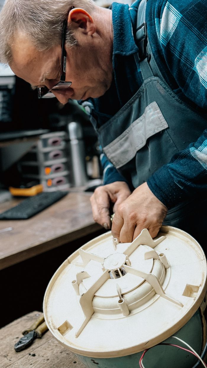 An experienced technician repairing a component of a home appliance on a workbench.
